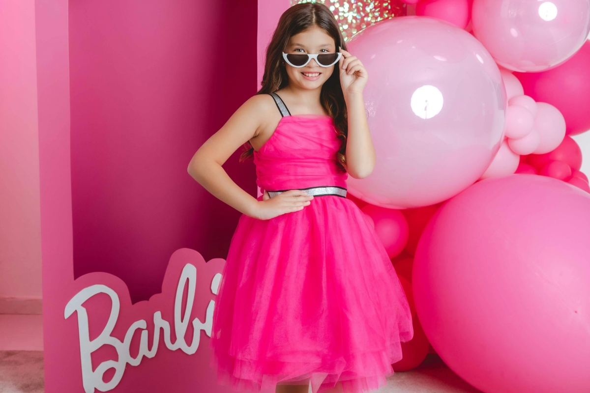 https://www.pexels.com/photo/a-girl-in-a-pink-dress-standing-in-front-of-a-large-barbie-box-16956404/